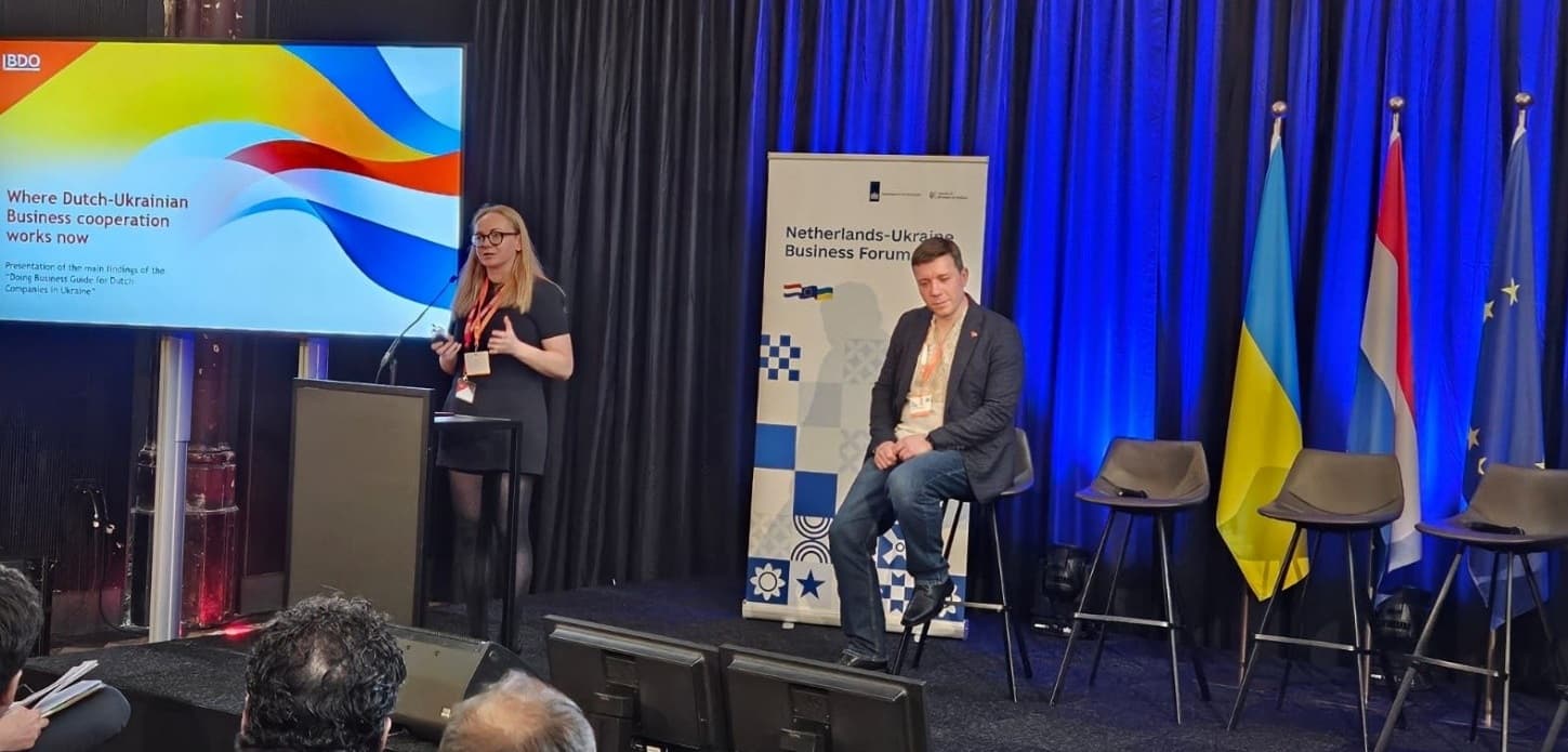 Representatives of BDO in Ukraine speaking on stage at the Netherlands–Ukraine Business Forum: presentation of an investment guide for Dutch companies, a screen displaying the presentation, and the flags of Ukraine, the Netherlands, and the EU in the background