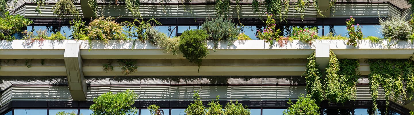 Facade of a modern building covered with plants and flowers on balconies and terraces, illustrating sustainable and eco-friendly architecture