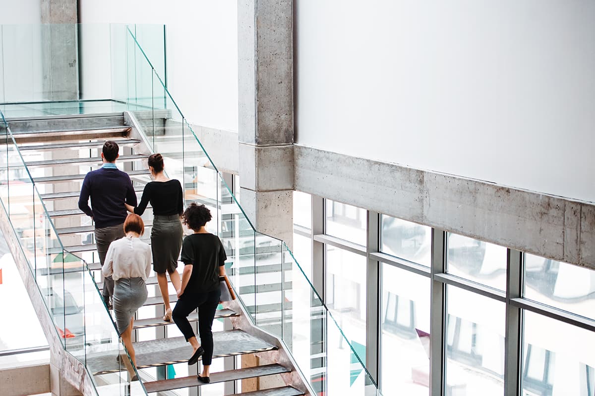 People walking up stairs in a modern office building, symbolizing ESG reporting preparation in accordance with European standards and sustainability requirements